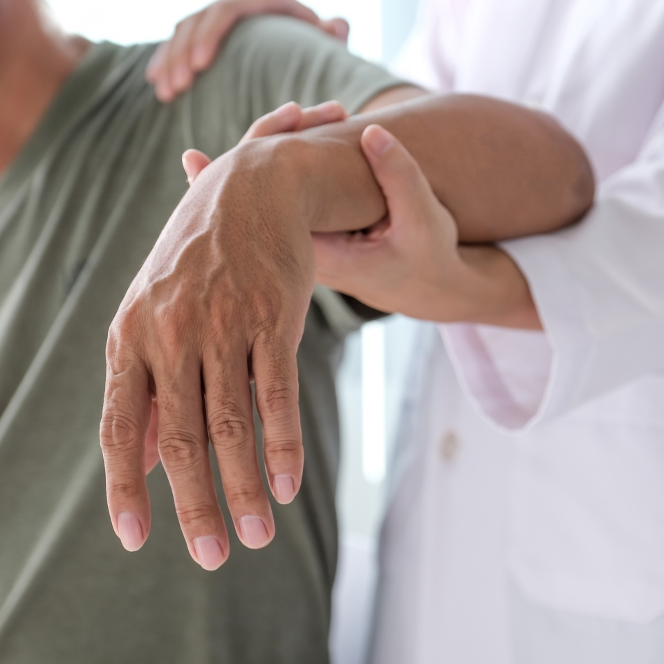 Female doctor hand rehab physical therapy by extending the pain shoulder of a patient. treatment with stretch exercises.