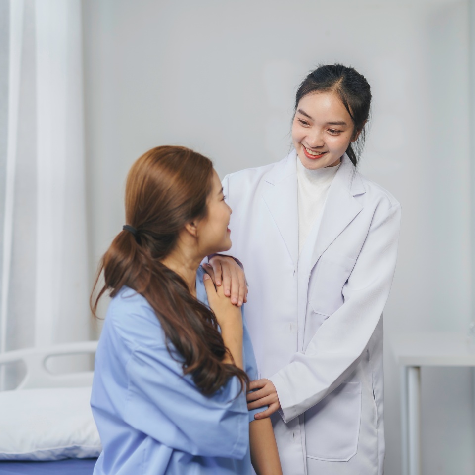 Compassionate female physician providing emotional support, touching patient's shoulder with care in well lit medical setting, conveying healing connection