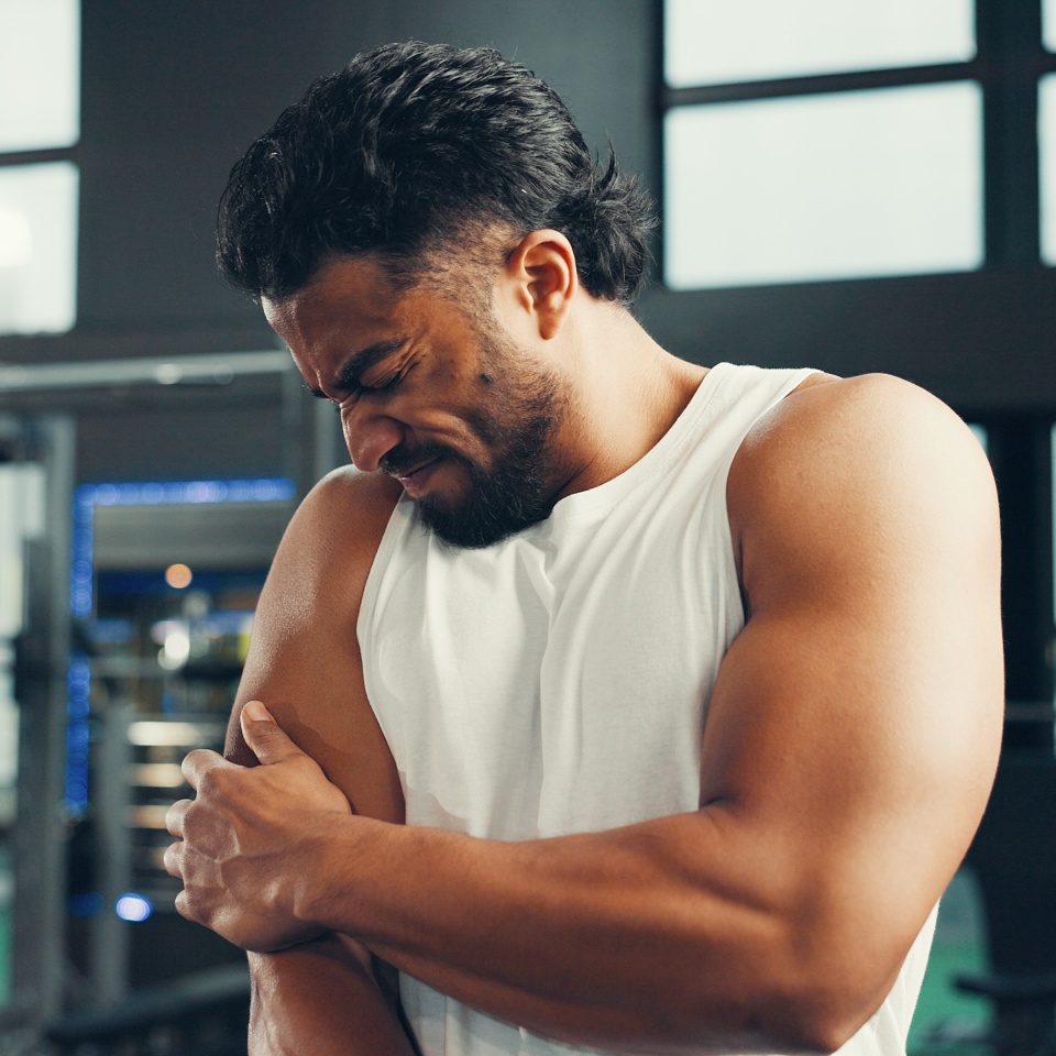 Man, fitness and arm with injury in gym for muscle tension, pain or workout accident. Male person, sore bicep or joint inflammation with ache, strain or pressure for intense exercise in health club.