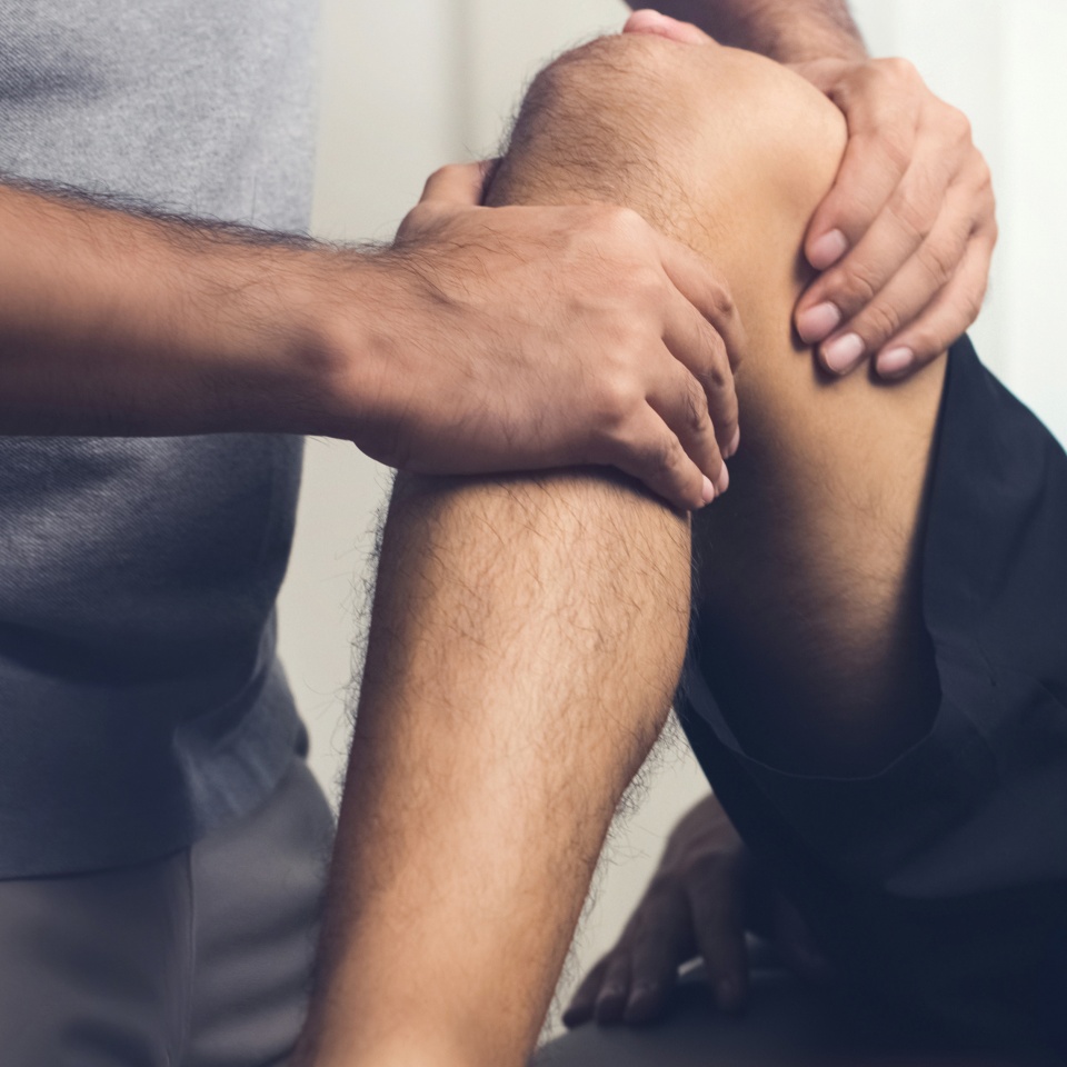 Therapist treating injured knee of athlete male patient - sport physical therapy concept, panoramic banner