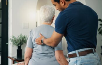 Old woman, chiropractor and consultation in nursing home with back assessment, support and healing. Senior person, orthopedic worker and help in retirement center for spine injury, recovery and exam