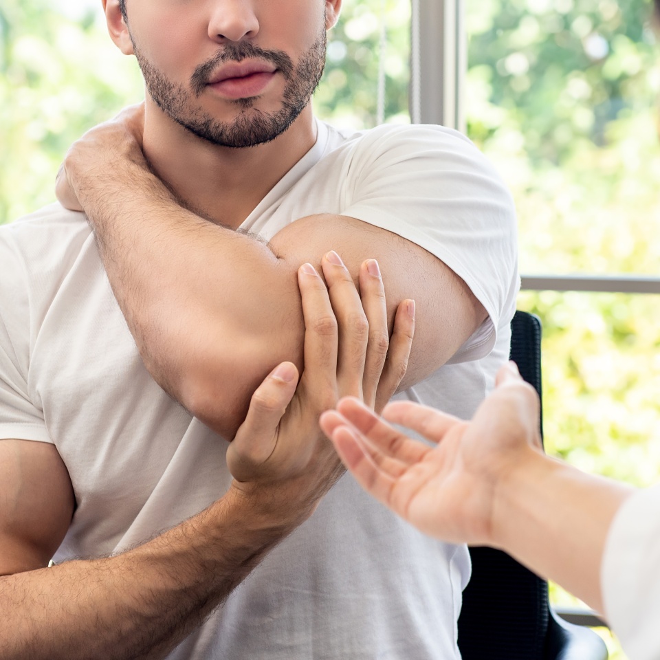Sportsman patient consulting with doctor for shoulder and tricep muscule pains in clinic
