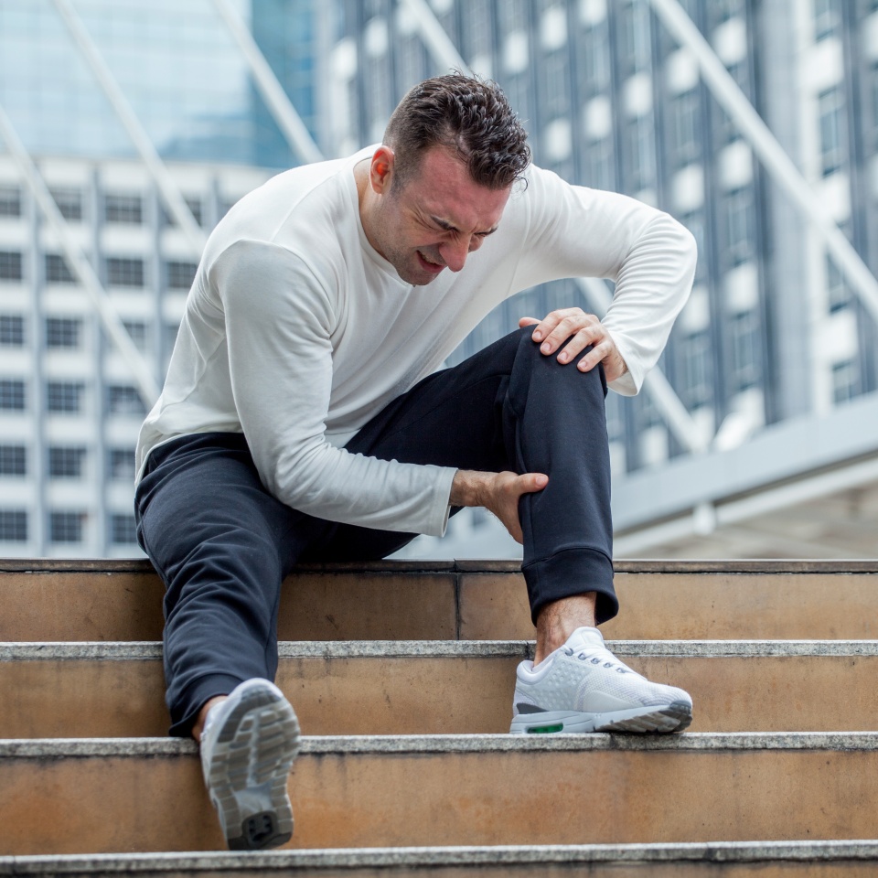 fitness man have knee pain sitting on steps of stair in the city. sport injury leg of run in urban , accident , exercise,workout