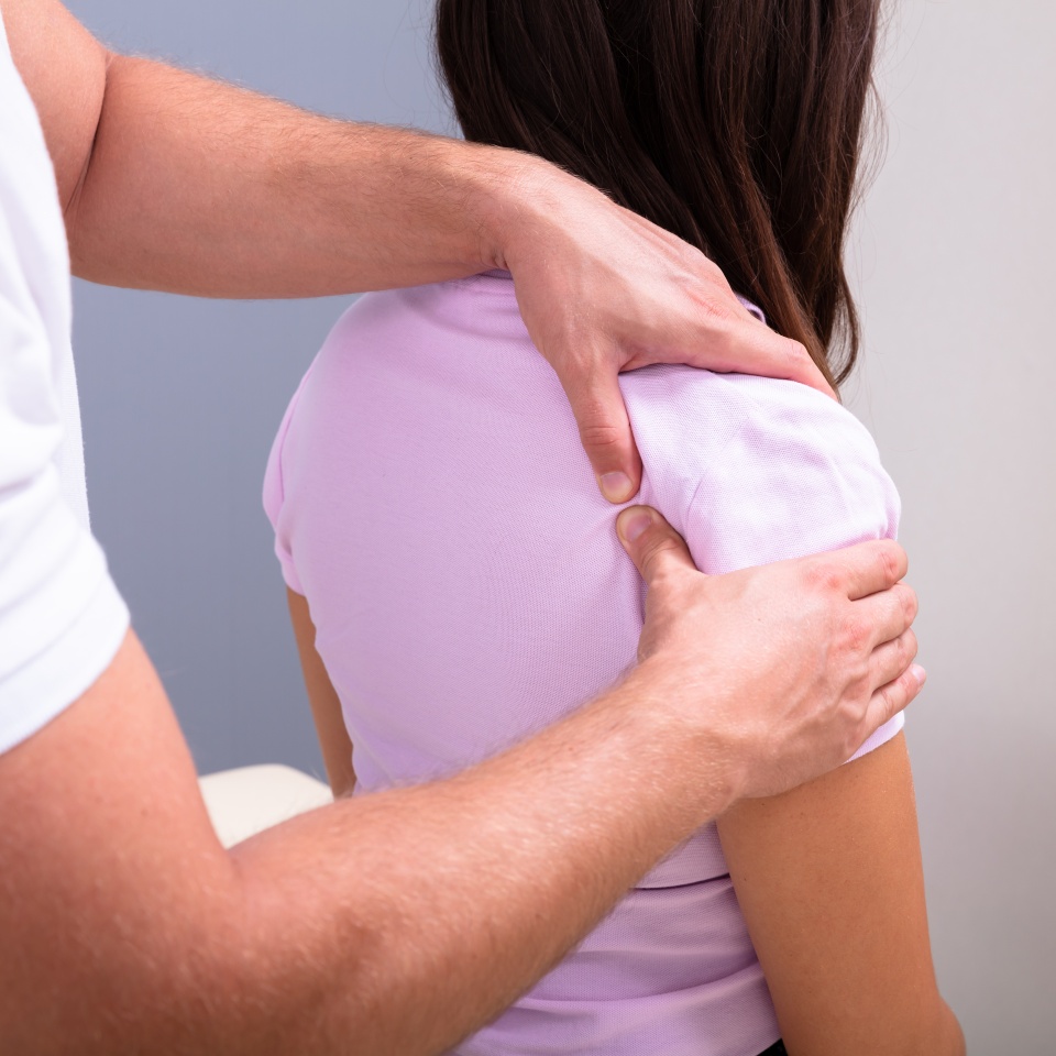 Professional Male Physical Therapist Massaging The Injured Shoulder Of A Woman Slowly In Medical Clinic