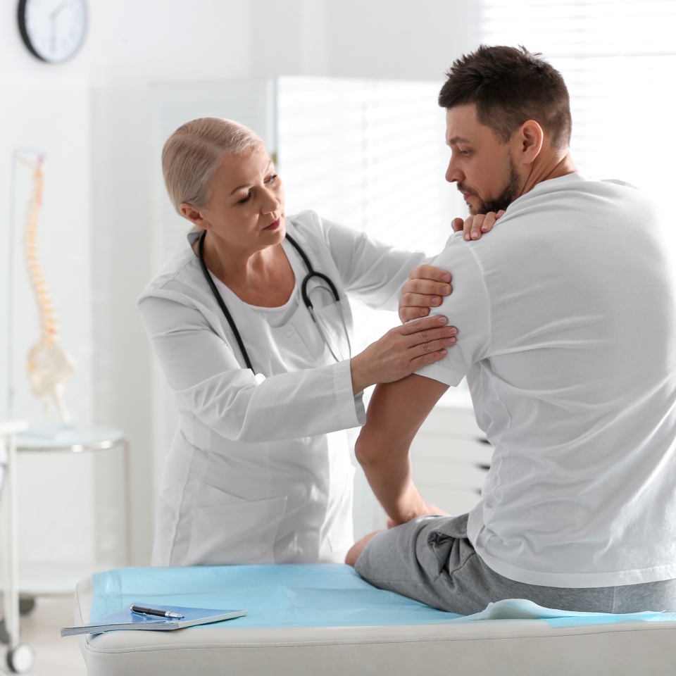 Male orthopedist examining patient's arm in clinic