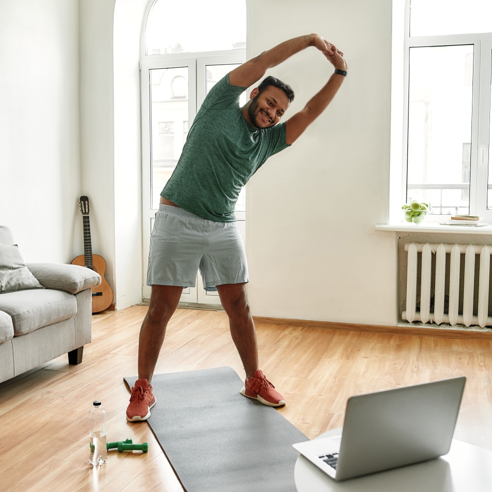 Personal trainer. Full length shot of male fitness instructor stretching his body while streaming, broadcasting video lesson on training at home using laptop. Sport, online gym concept. Web Banner
