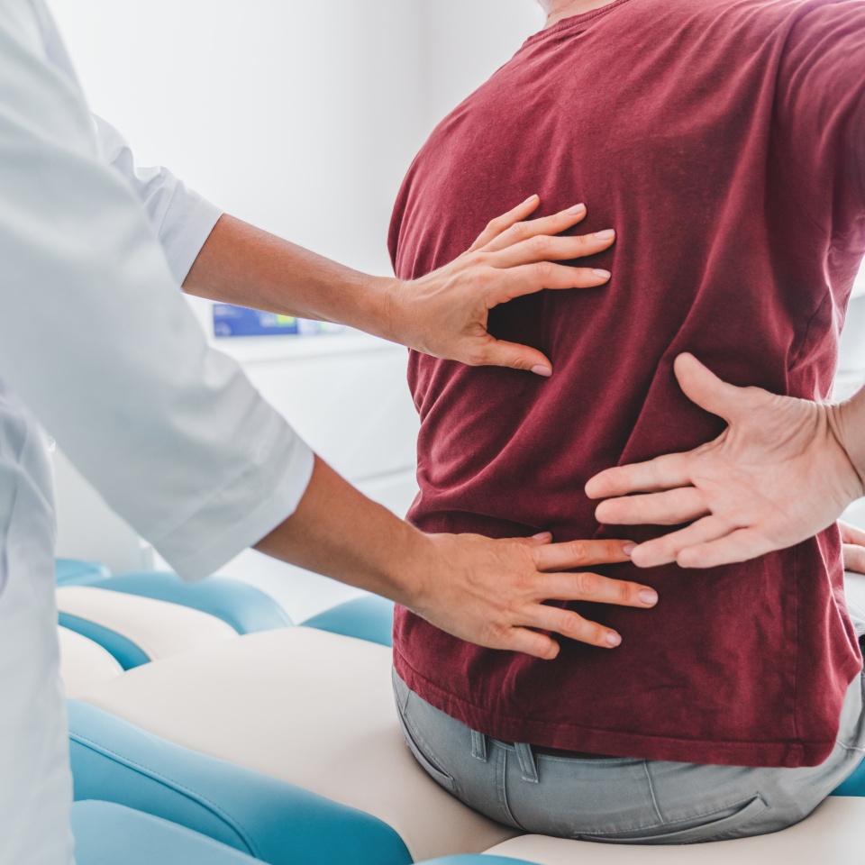 Cropped close up of female orthopedist examining patient's back in clinic