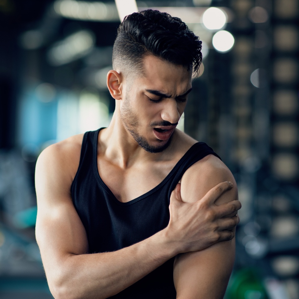 Portrait Of Young Arab Man With Shoulder Pain Suffering Sport Injury During Training At Gym, Middle Eastern Male Athlete Having Trauma After Fitness Workout, Rubbing Painful Area, Closeup