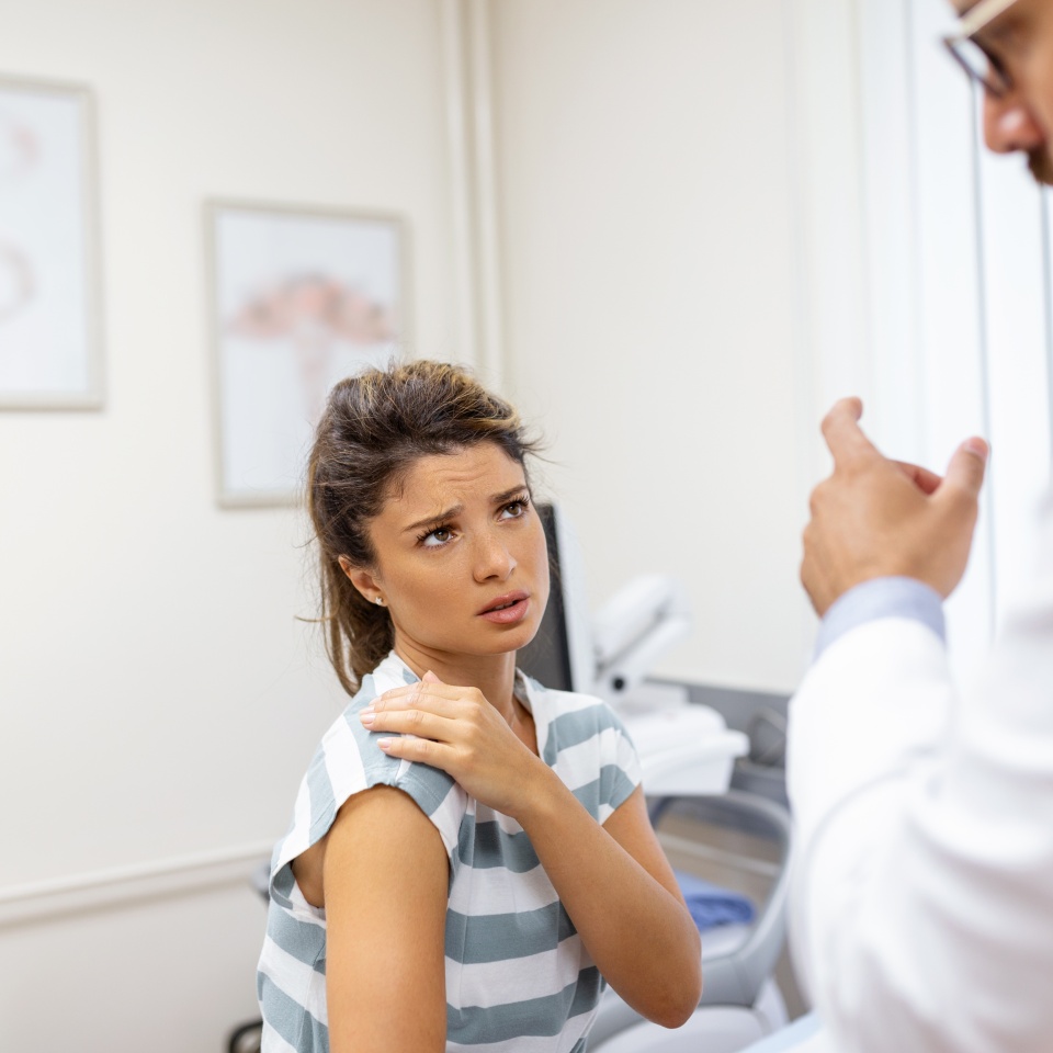 Woman having a shoulder pain. Doctor working in the office and listening to the patient, she is explaining her symptoms, healtcare and assistance concept