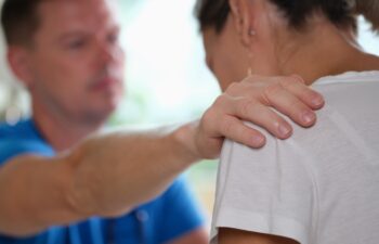 Doctor puts sympathetic hand on clinic woman shoulder. Mental health problems and nervous stress with depression in women
