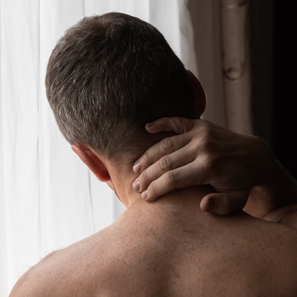 Back of sporty young European man with a pain in the neck