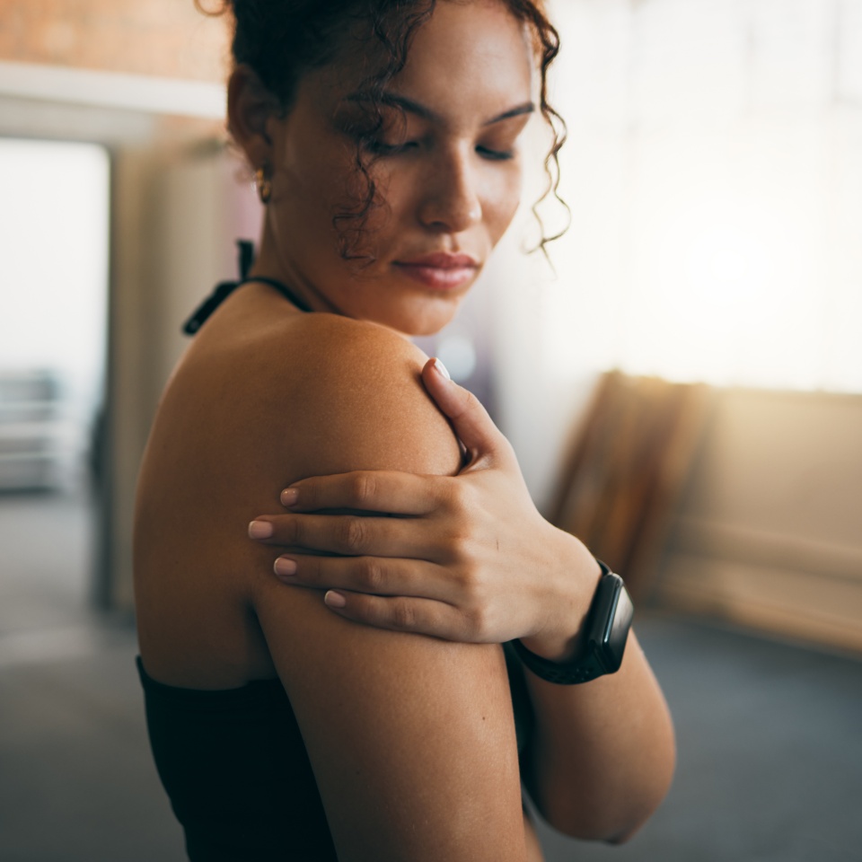Woman, fitness and shoulder injury from sports workout, exercise or training at the gym indoors. Female holding arm after painful sport accident, inflammation or bruise from intense exercising.
