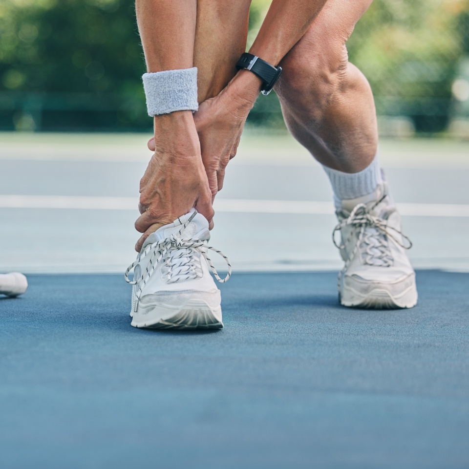 Tennis player or woman with ankle pain on sports ground for healthcare risk, muscle accident or training problem. Competition, game and athlete on fitness court with foot injury and legs massage.