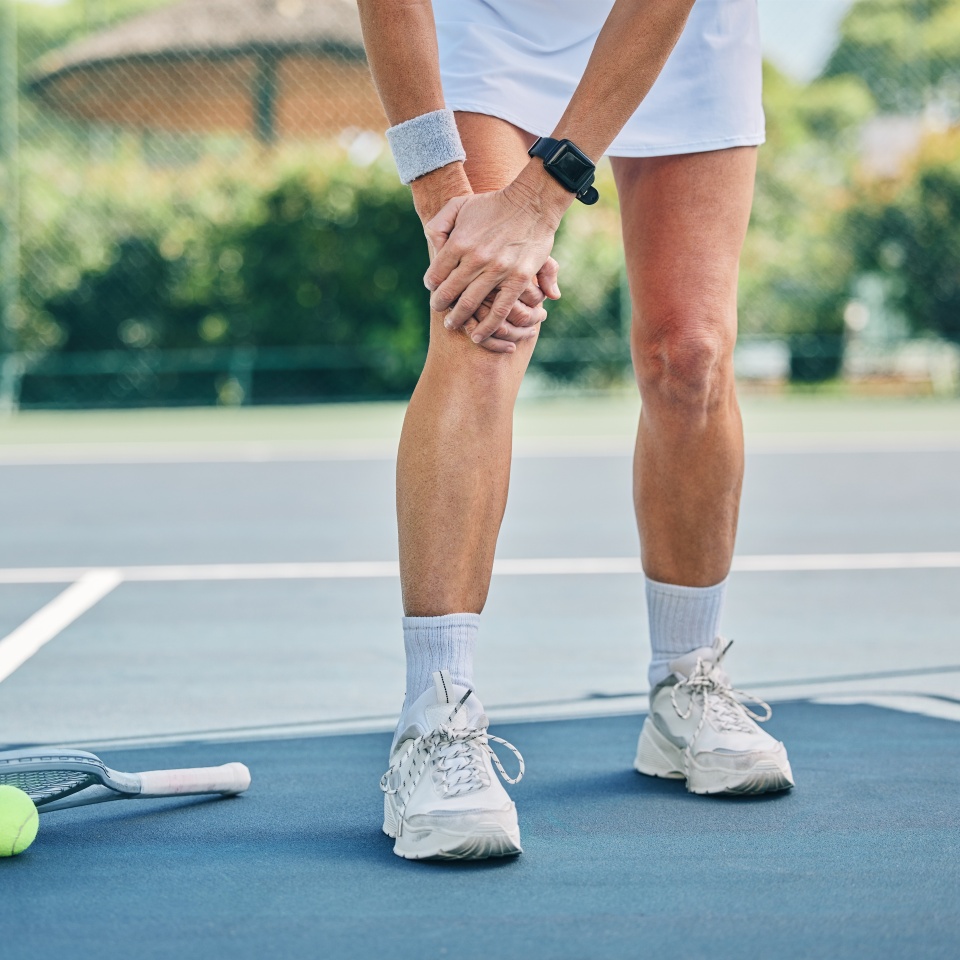 Tennis court, woman knee injury and training outdoor for fitness, health or wellness by blurred background. Summer, sports and exercise with pain in legs at game, contest or competition in sunshine.