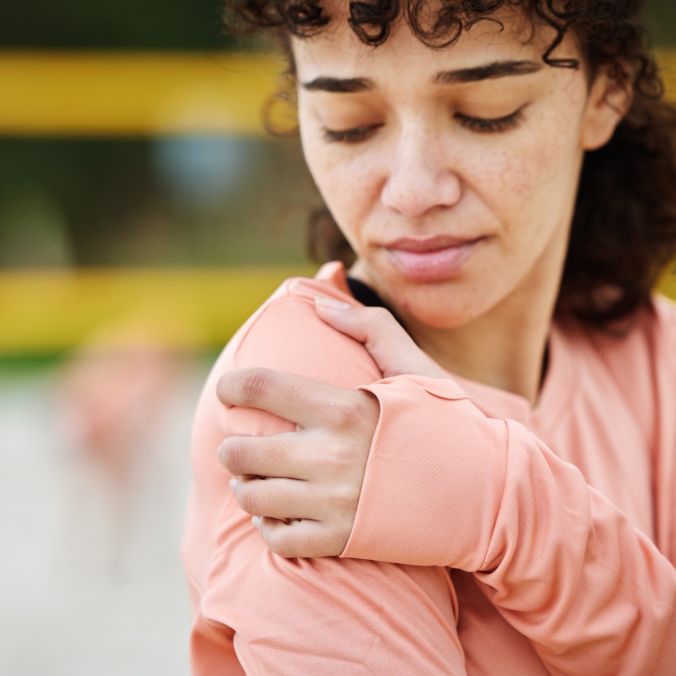 Shoulder pain, fitness and woman with injury at beach after volleyball accident, workout or training. Health, sports and female with fibromyalgia, inflammation or painful arm, arthritis or tendinitis.