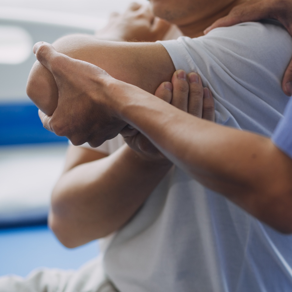 Doctor or Physiotherapist working examining treating injured arm of athlete male patient, stretching and exercise, Doing the Rehabilitation therapy pain in clinic.