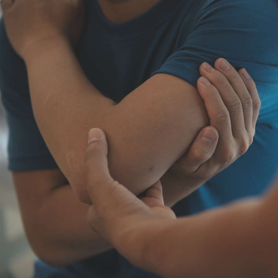 Doctor or Physiotherapist working examining treating injured arm of athlete male patient, stretching and exercise, Doing the Rehabilitation therapy pain in clinic.