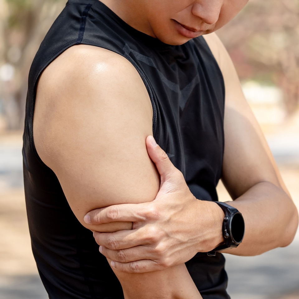 Bicep tendonitis or front arm muscle inflammation. Asian athlete man suffering from upper arm pain while doing outdoor exercise in the park. Sport injury concept