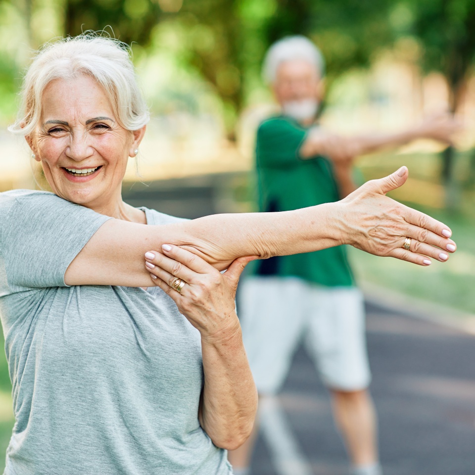 Portrait os a happy beautiful elderly senior mature woman exercising and stretching outdoors