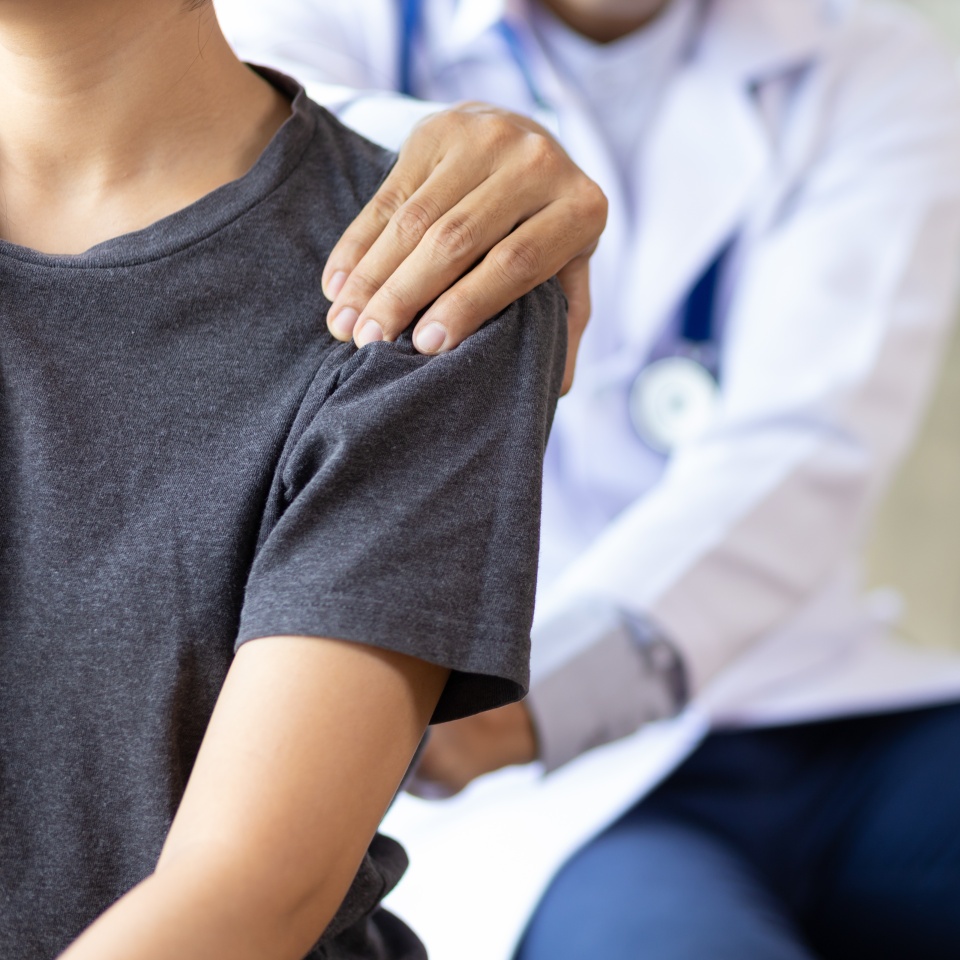 Doctor examining woman back pain in examination room. Doctor practicing back and shoulder physiotherapy for female patient in hospital.