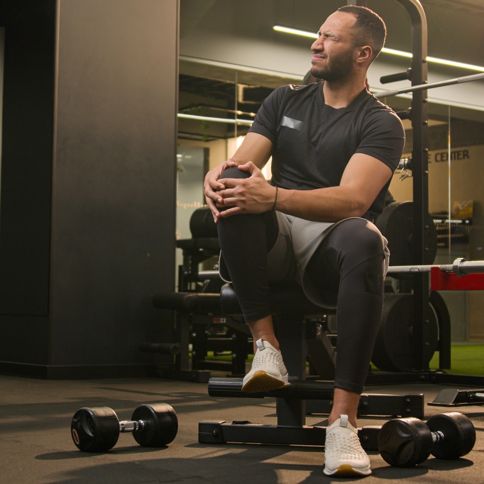 African American unwell man sad suffering with knee pain in sport club workout trauma sporty man muscle ache sportsman athlete male injuring leg in training painful injury in fitness gym ache damage. High quality 4k footage