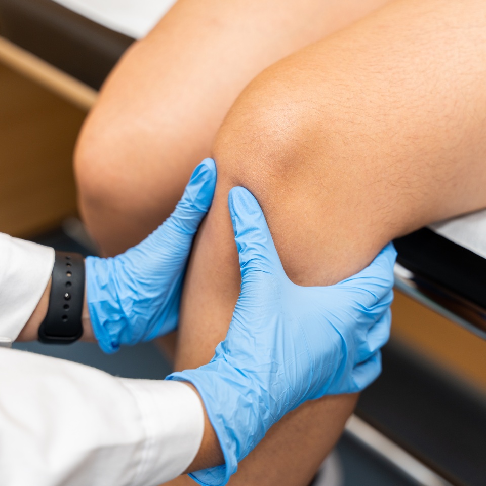 An orthopedic trauma doctor examines the knee joint of a woman who has pain