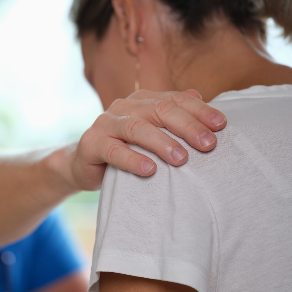 Doctor puts sympathetic hand on clinic woman shoulder. Mental health problems and nervous stress with depression in women