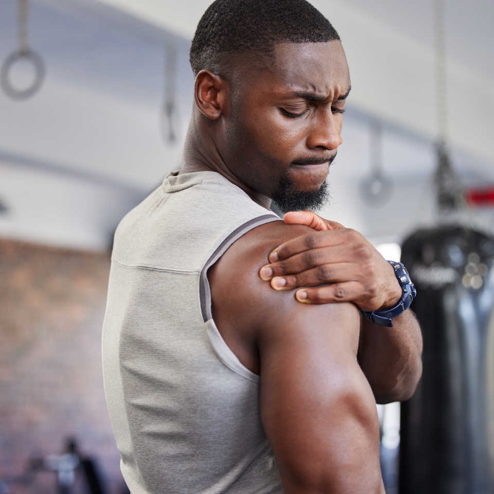 Exercise, black man and shoulder pain for training, fitness and workout for wellness in gym. Nigerian male, athlete and body care with pain, tired and injury for ache, strong and orthopedic problem.