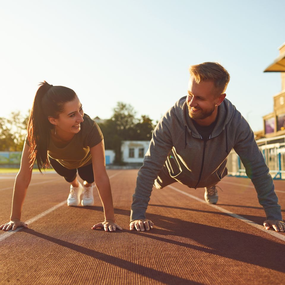 Young couple doing pushups in the stadium in the morning.