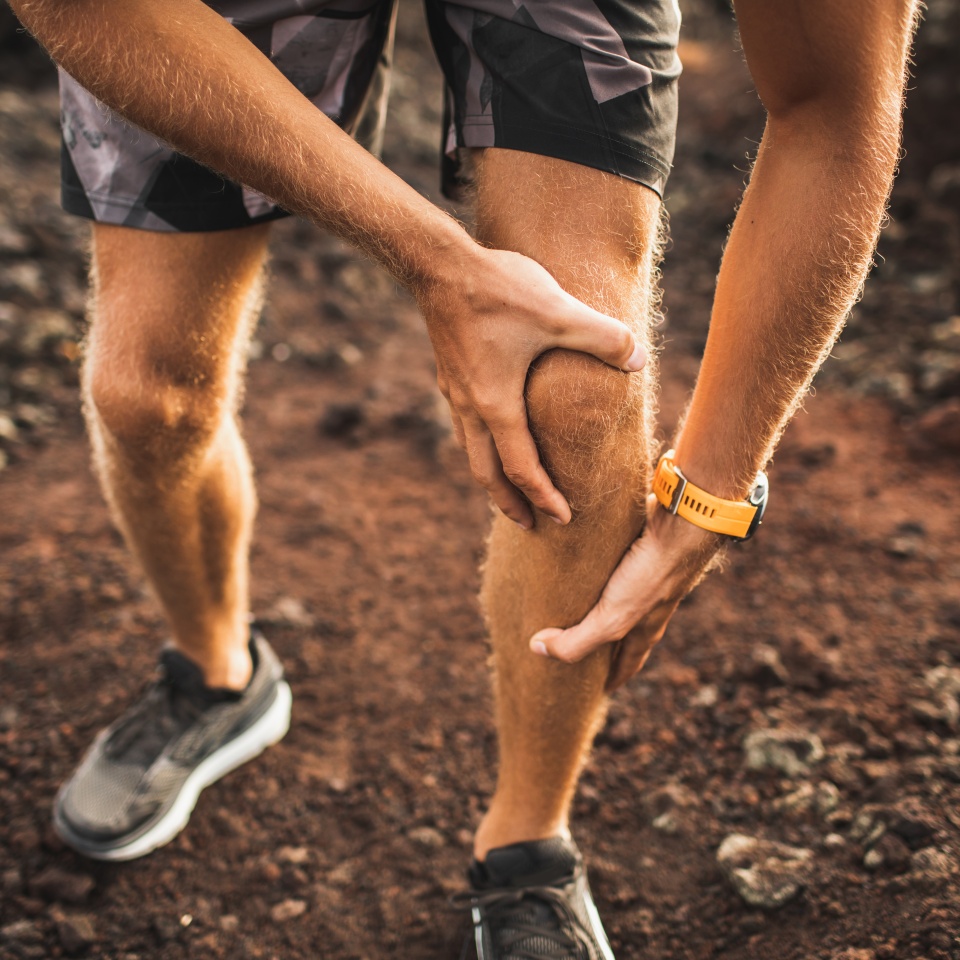 Knee injury on running outdoors. Man holding knee by hands close-up and suffering with pain. Sprain ligament or meniscus problem.