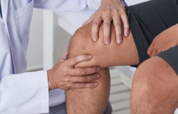 Close-up image of doctor cheking knee of male patient