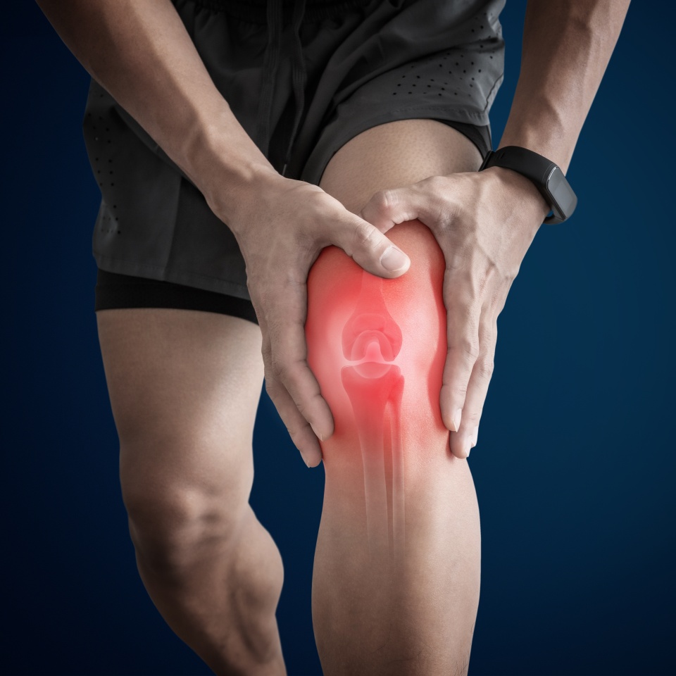 A person holding their knee in pain, with a glowing red highlight and an illustration of the knee joint indicating discomfort or injury.